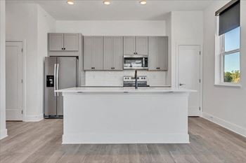 A modern kitchen with a white island and stainless steel appliances.